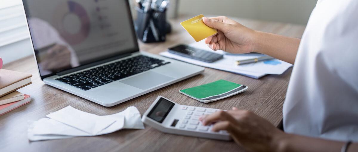 Woman holding credit card payment internet banking or shopping concept. calculating tax or payment. laptop, credit card, calculator on desk